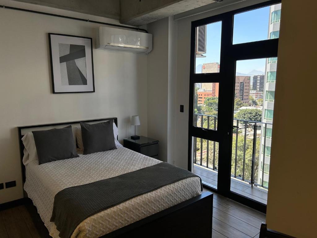 a bedroom with a bed and a large window at EÓN 9 - Moderno, vista volcán, aire acondicionado in Guatemala