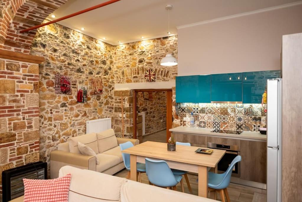 キオスにあるΠΕΤΡΙΝΟ ΣΠΙΤΙ ΣΤΟΝ ΚΑΜΠΟ ΧΙΟΥのレンガの壁のリビングルームとキッチンが備わります。