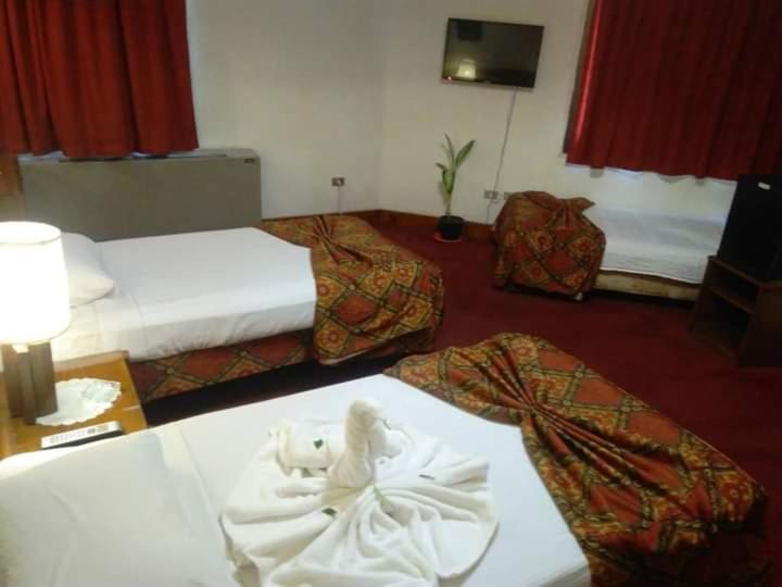 una habitación de hotel con 2 camas y una mesa con un visor blanco en Salvatore Room -Cairo Downtown en El Cairo