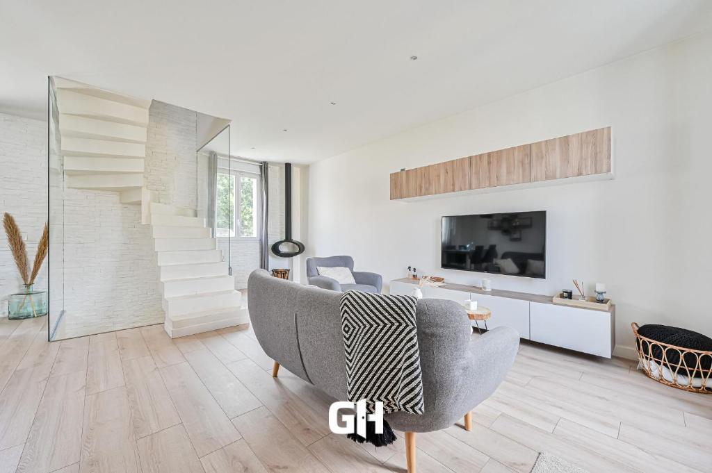 un salon avec un canapé et une télévision dans l'établissement La Casa Blanca - 6 personnes proche Disney & Paris, à Le Raincy