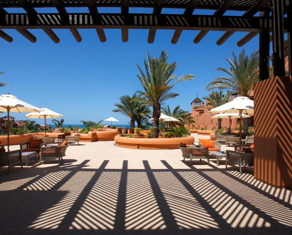 a patio with tables and chairs and umbrellas at Royal Hideaway Sancti Petri in Chiclana de la Frontera