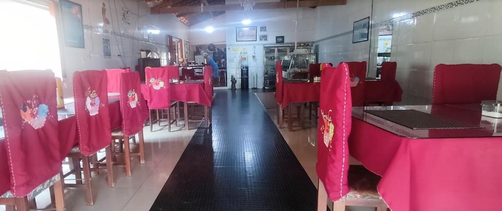 un comedor con mesas y sillas rojas en HOTEL E RESTAURANTE BOM GOSTO, 