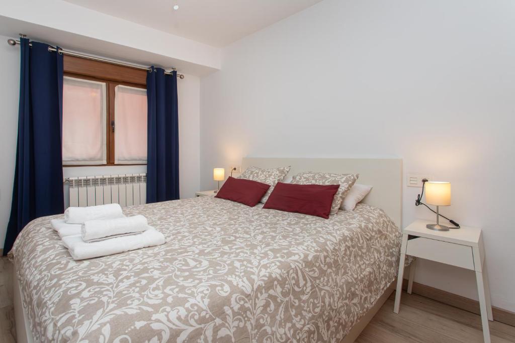 a bedroom with a bed with blue curtains and a window at La Plaza de Cangas Apartamento Turistico in Cangas de Onís