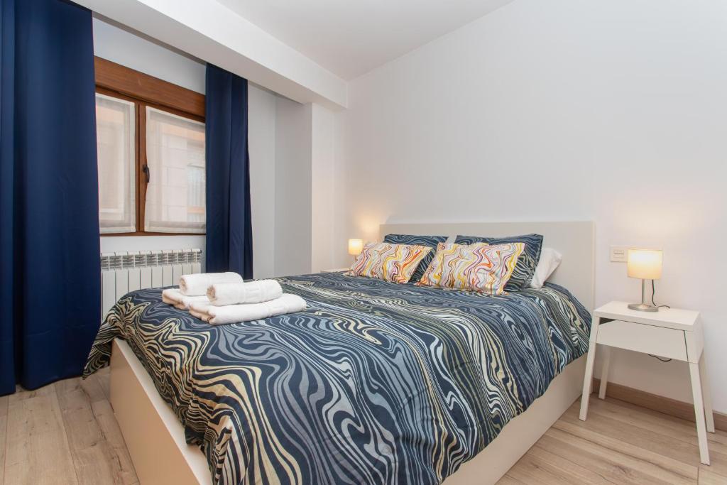 a bedroom with a large bed with blue curtains at La Plaza de Cangas Apartamento Turistico in Cangas de Onís