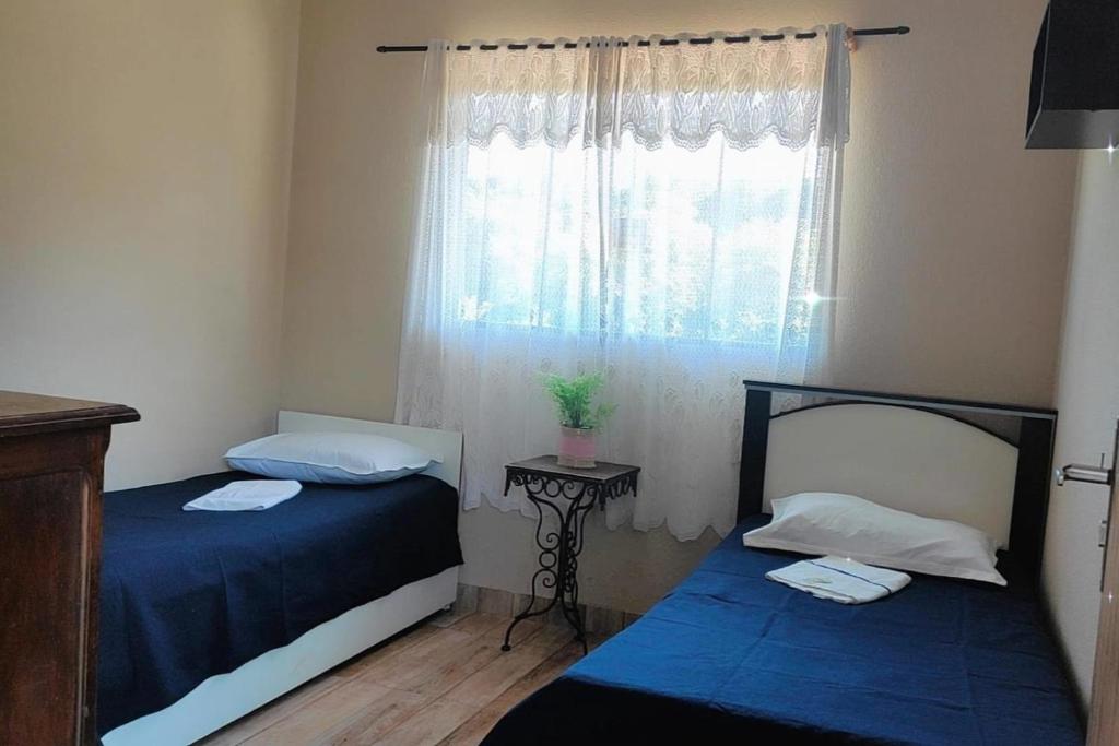 Duas camas num pequeno quarto com uma janela em Pousada Apucarana em Apucarana