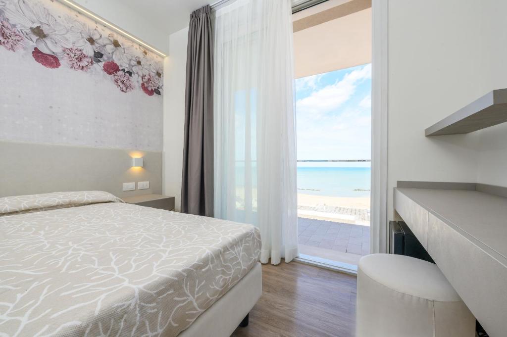 una camera con letto e vista sulla spiaggia di Hotel Harmony a Rimini