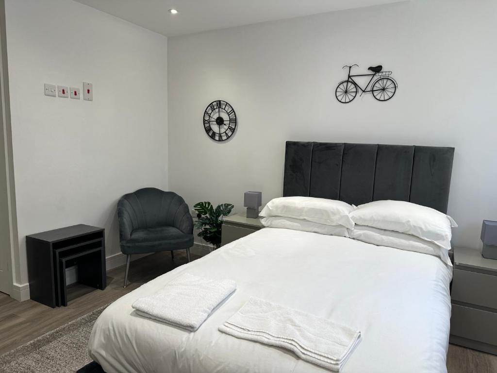 sypialnia z łóżkiem, krzesłem i zegarem w obiekcie Studio Flat in Luton Town Centre w Luton