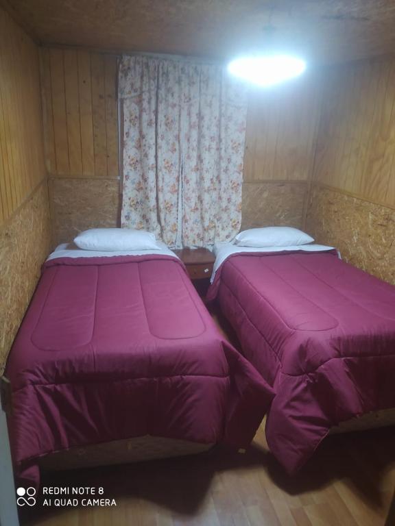 two beds sitting next to each other in a room at Hostal norteña in Villa O'Higgins