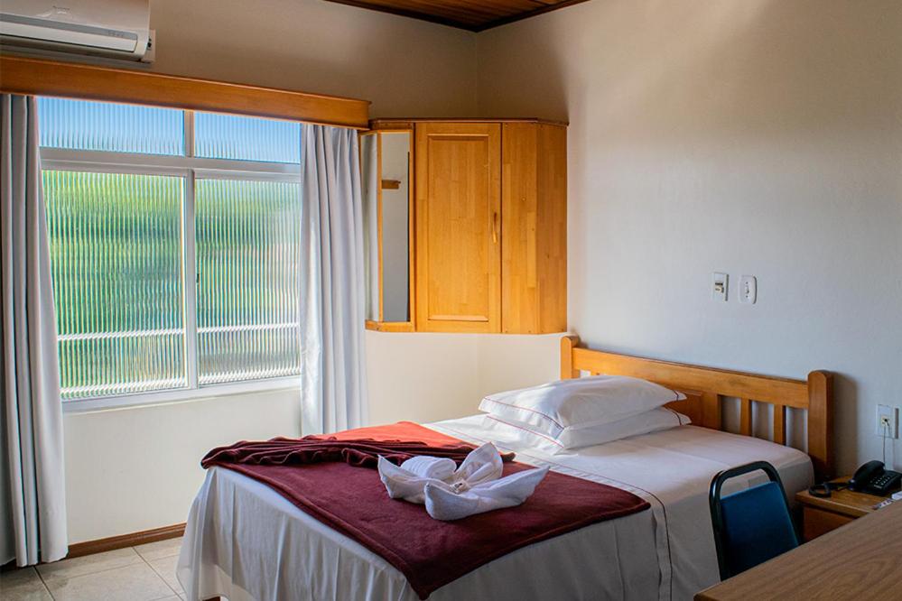 een slaapkamer met een bed en een groot raam bij HOTEL TAIÓ in Taió