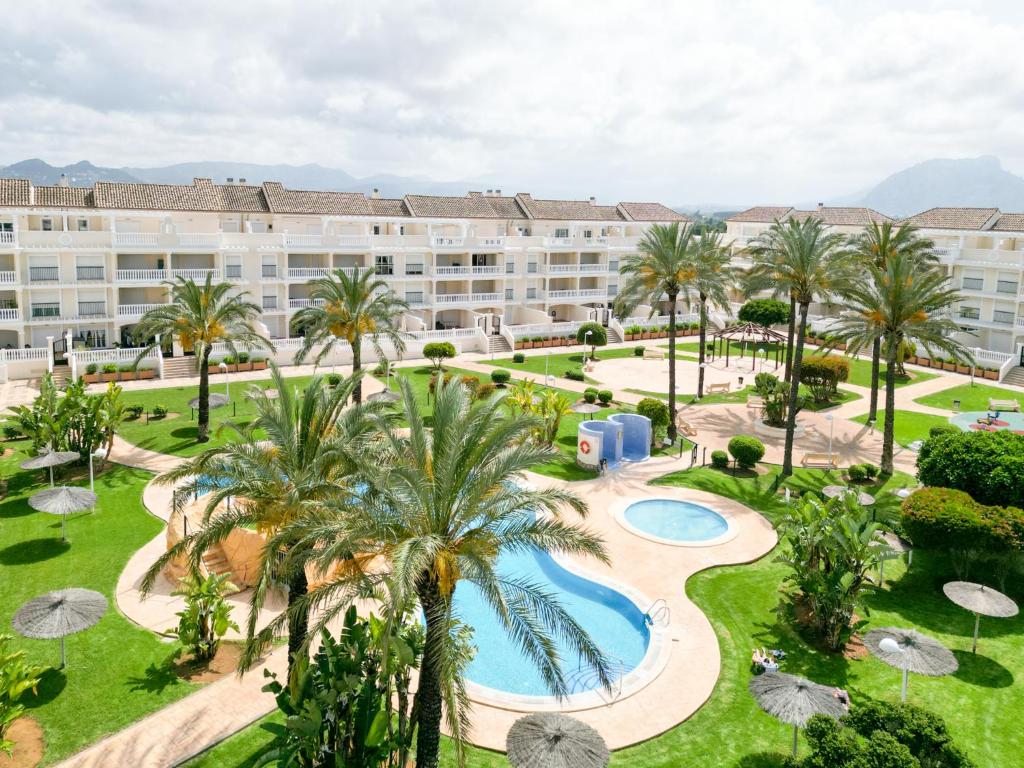 uma vista aérea de um resort com uma piscina e palmeiras em Apartamento planta baja Residencial Aquamarina by costablancarent em Denia