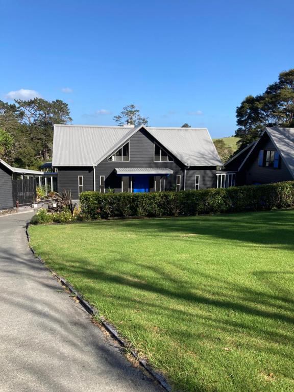 a large black house with a grass yard at Fantail River Lodge in Haruru