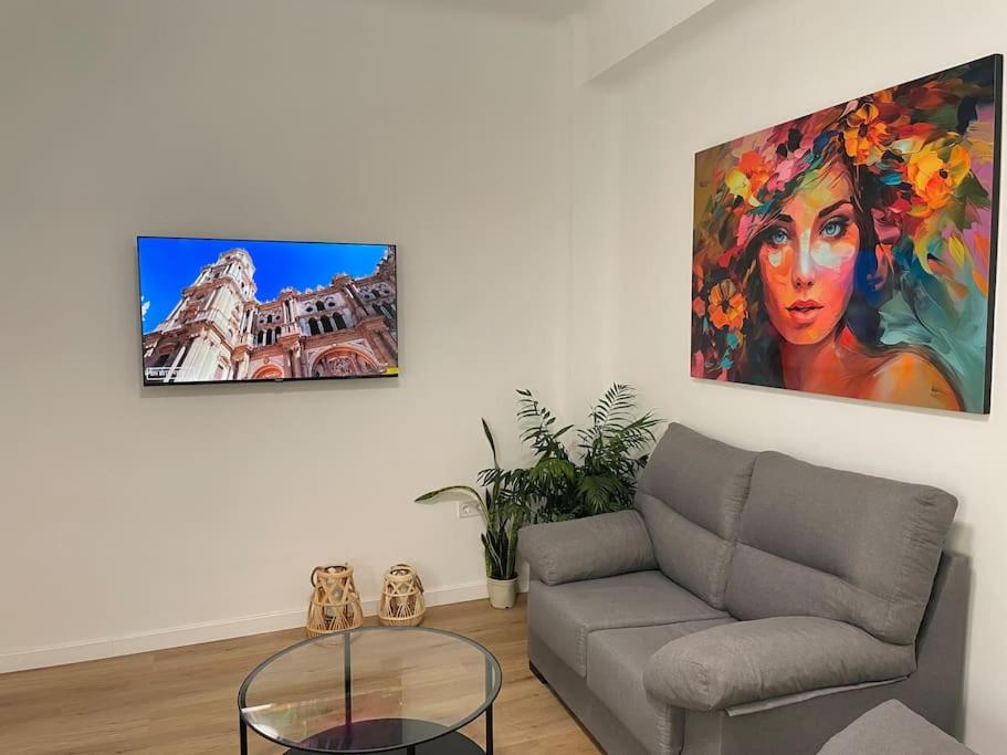 ein Wohnzimmer mit einem Sofa und einem Gemälde an der Wand in der Unterkunft Málaga-Centro in Málaga