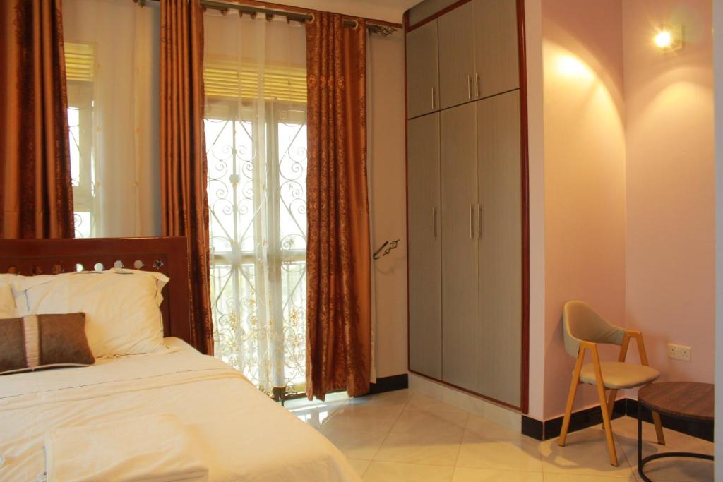- une chambre avec un lit, une chaise et une fenêtre dans l'établissement S A Apartments, à Kampala