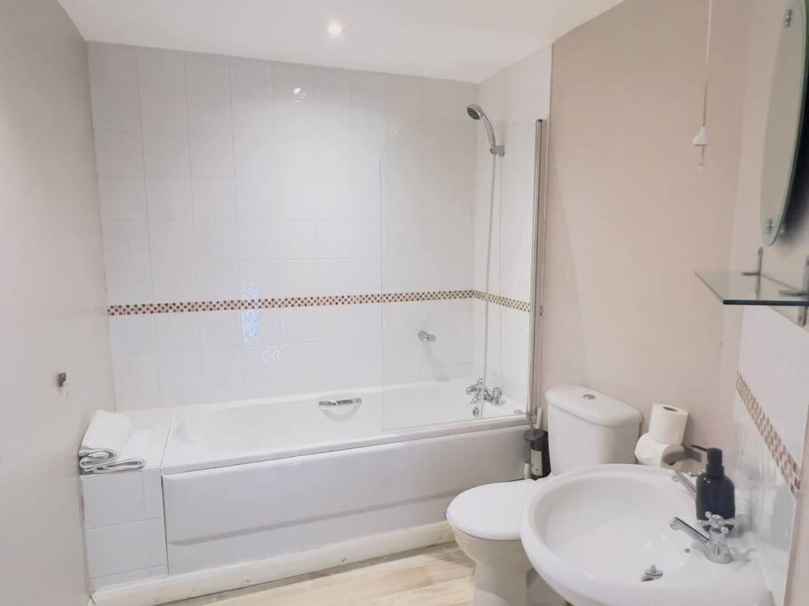 een witte badkamer met een bad, een toilet en een wastafel bij Starview Apartment 101 in Colchester