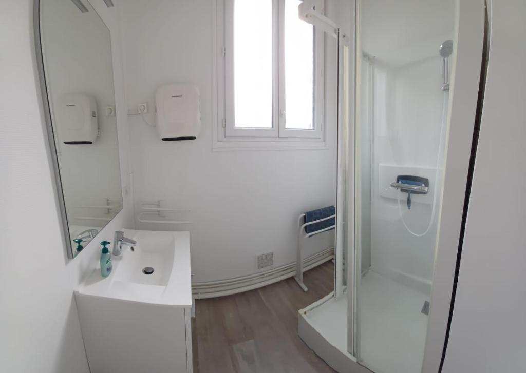 a white bathroom with a shower and a sink at Le Rayon Vert vue mer in Fécamp