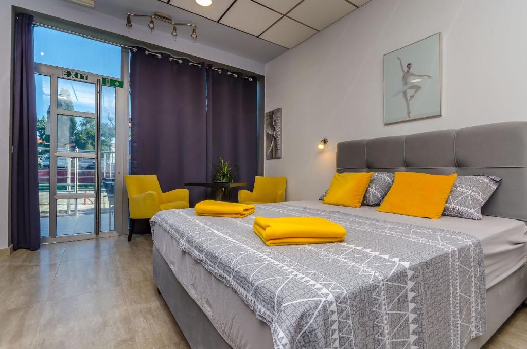 um quarto com uma cama grande e almofadas amarelas em Apartments Stay em Kaštela