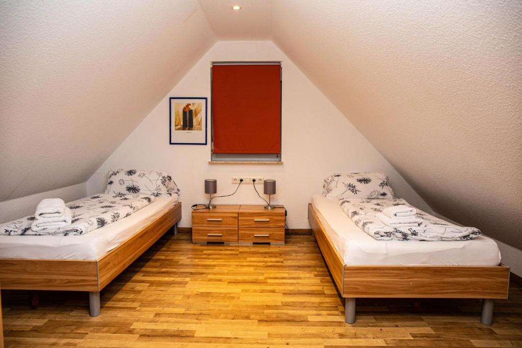 two beds in a attic room with wooden floors at Ferienwohnungen Saida Wohnung 10 in Norden