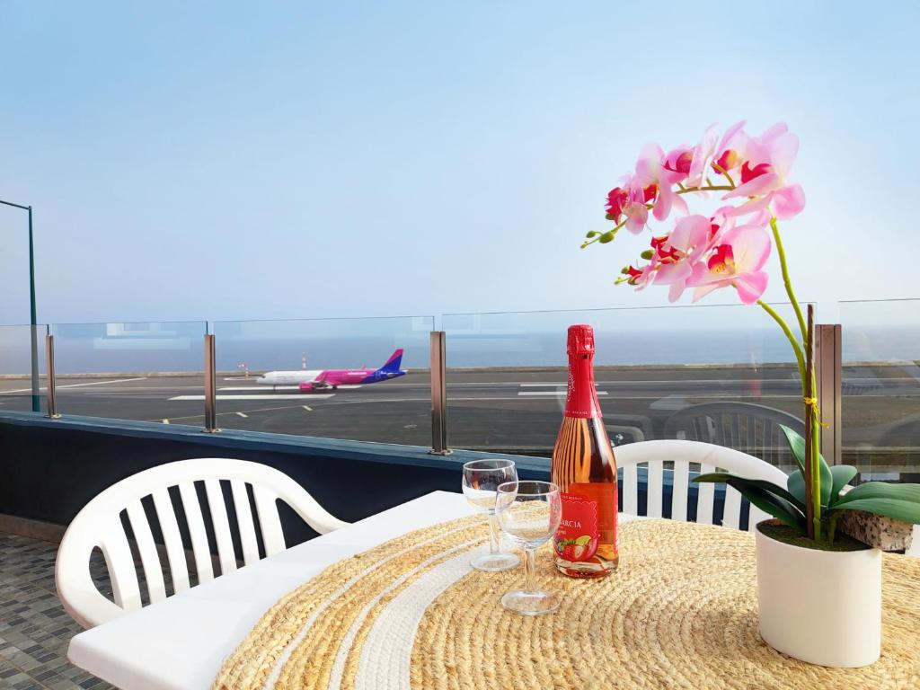 een tafel met een fles wijn en bloemen erop bij GATEONE AL Airport View House in Machico