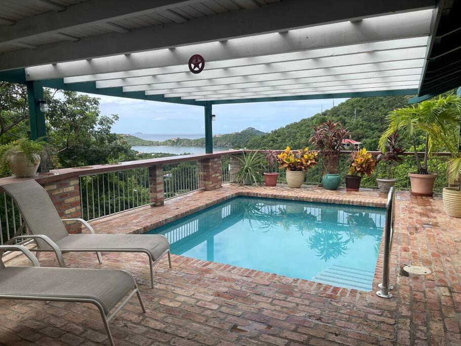 a swimming pool on a brick patio with a pergola at JJ's Getaway in Cruz Bay