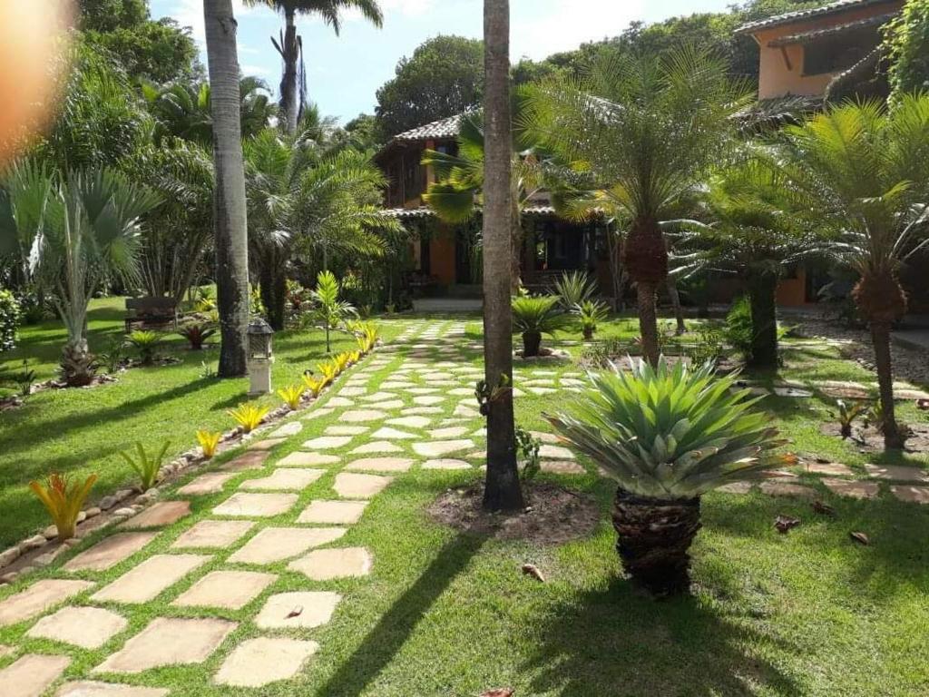 un giardino con palme e un vialetto di pousada mandala a Cumuruxatiba