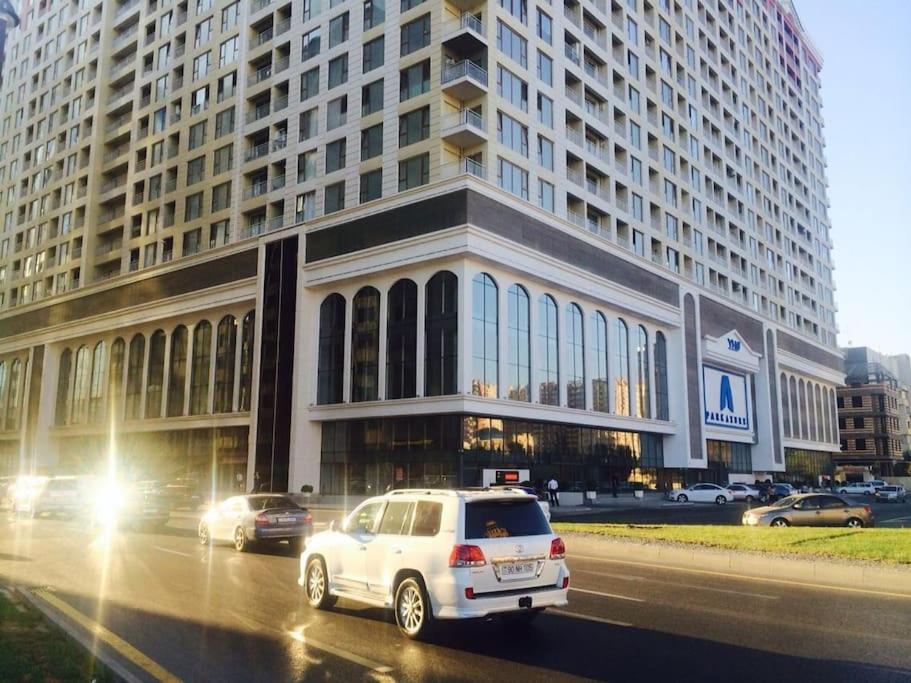 a white car driving in front of a large building at The Park Azure Residence - Baku in Baku
