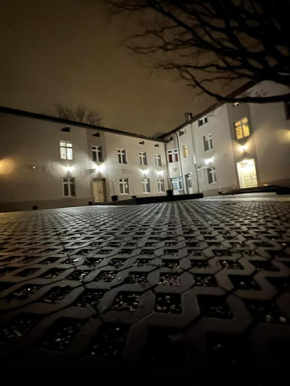 a large building at night with a cobblestone street at Apartamenty Retro in Dąbrowa Górnicza