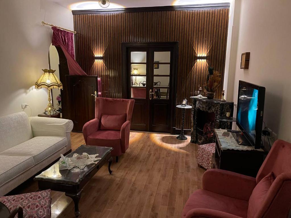 - un salon avec un canapé, des chaises et une télévision dans l'établissement Wonderful Apartment Place in Dokki, au Caire