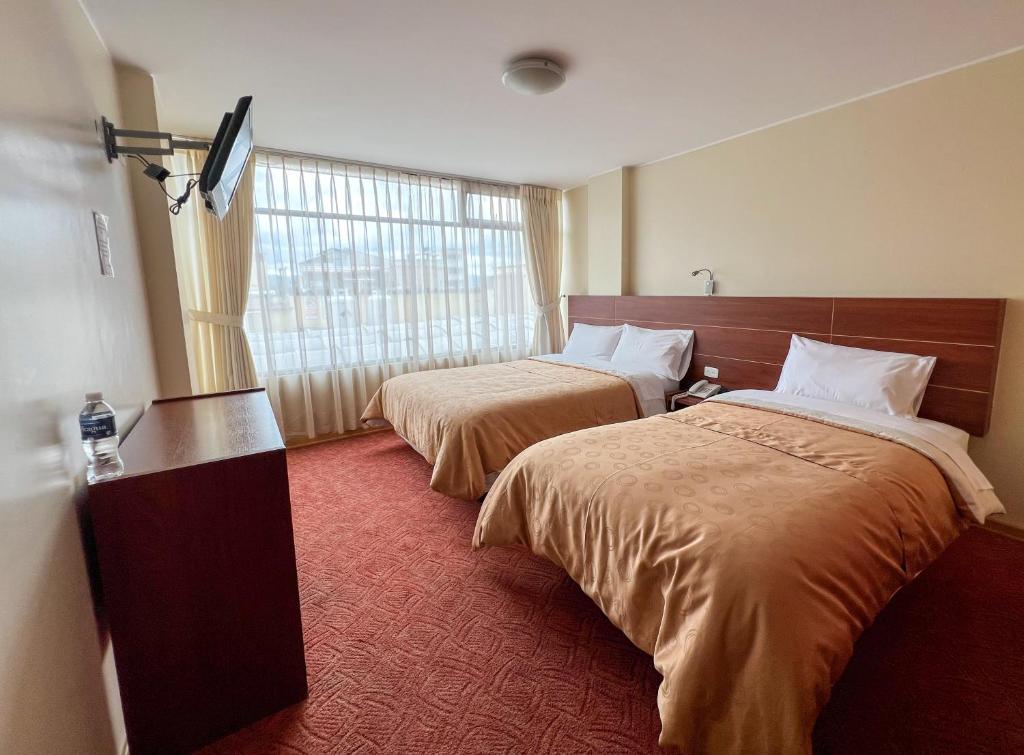 Habitación de hotel con 2 camas y ventana en HOTEL FLOR DE LOS ANDES en Tulcán
