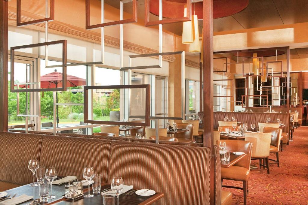 a dining room with tables and chairs and windows at The Westin Washington Dulles Airport in Herndon