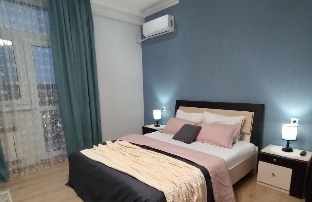 Un dormitorio con una cama con almohadas rosas y una ventana en Однокомнатные апартаменты в золотом квадрате ЖК GREEN PLAZA en Aktau