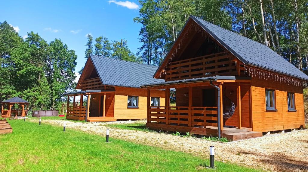 een grote houten hut met een zwart dak bij Las Lorien - wynajem domków letniskowych 2.0 in Roczyny