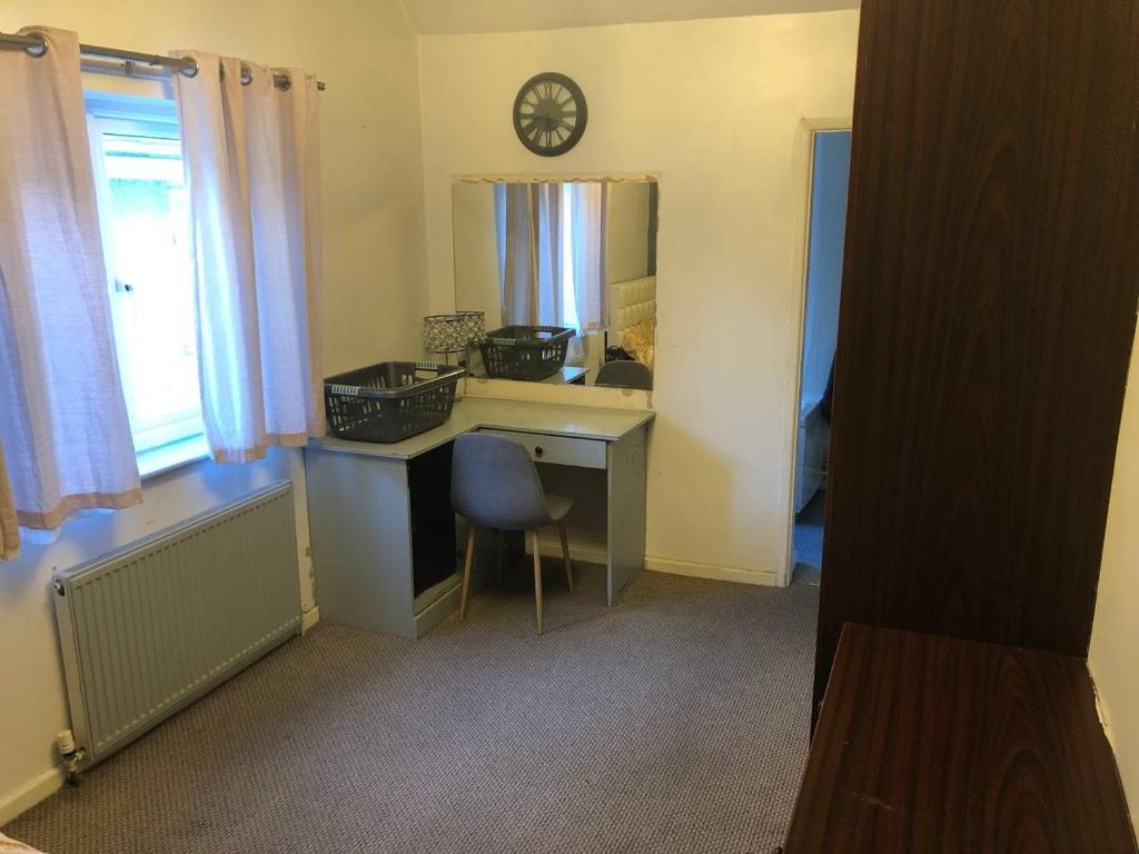 Comfy keats place في Bushbury: غرفة مع مكتب ومرآة وساعة