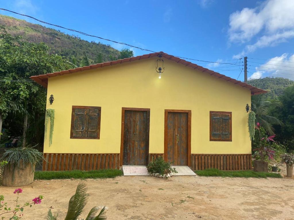 ein gelbes Haus mit Holztüren in einem Hof in der Unterkunft Ferrari Casa Nostra in Santa Teresa