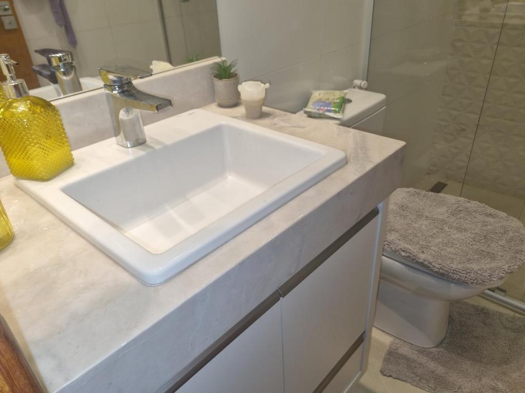 a white bathroom with a sink and a toilet at Quarto em casa com lazer completo in Indaiatuba