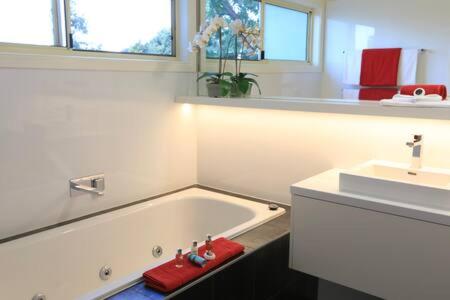 uma casa de banho branca com uma banheira e um lavatório em Inglenook Luxury Spa Cottage for Two em Cowes