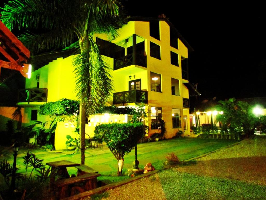 a yellow building with a palm tree in front of it at Pousada Villa Guimaraes in Chapada dos Guimarães