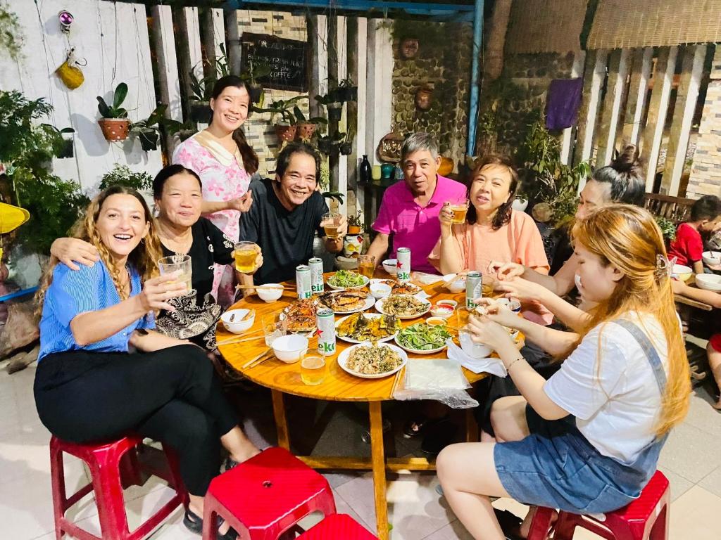 Un groupe de personnes assises autour d'une table à manger dans l'établissement Golden Lantern Tam Thanh Homestay, à Tam Kỳ