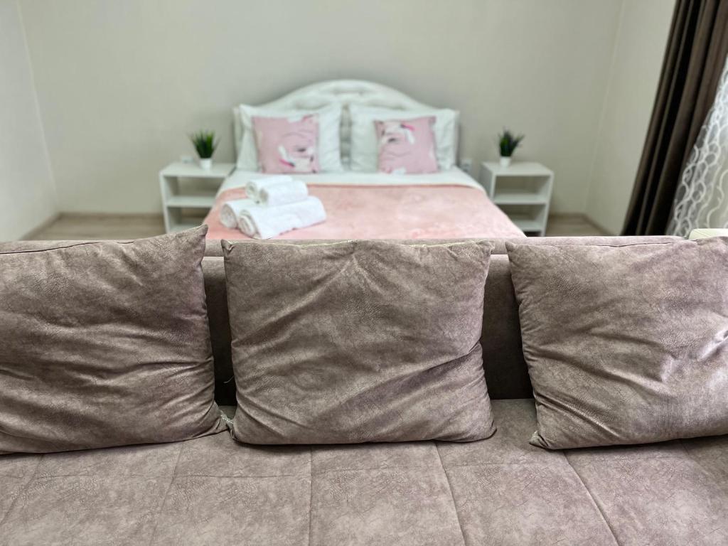 un sofá con almohadas y una cama en una habitación en Квартира Rose, en Öskemen