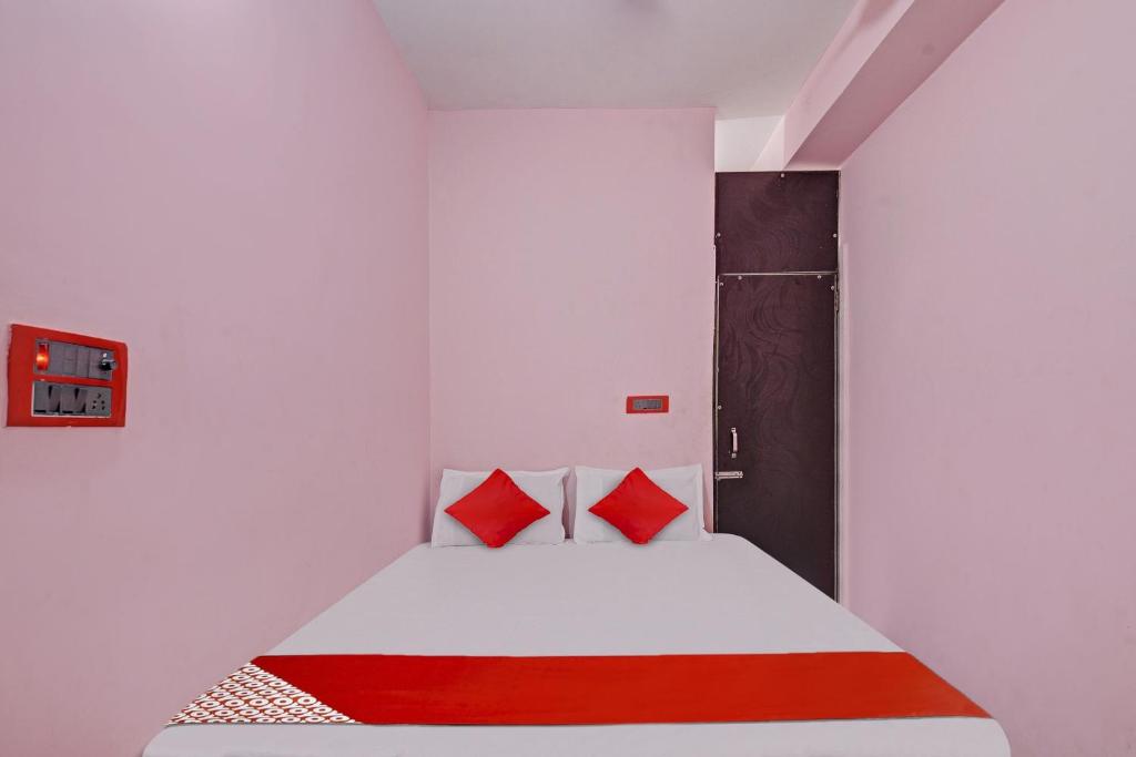 um quarto com uma cama branca e almofadas vermelhas em Flagship Red Rose Hotel & Banquet em Dhanbad