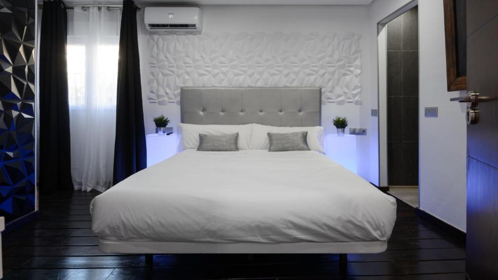 een slaapkamer met een groot wit bed met 2 kussens bij Malaga Chic jacuzzi y playa in Málaga