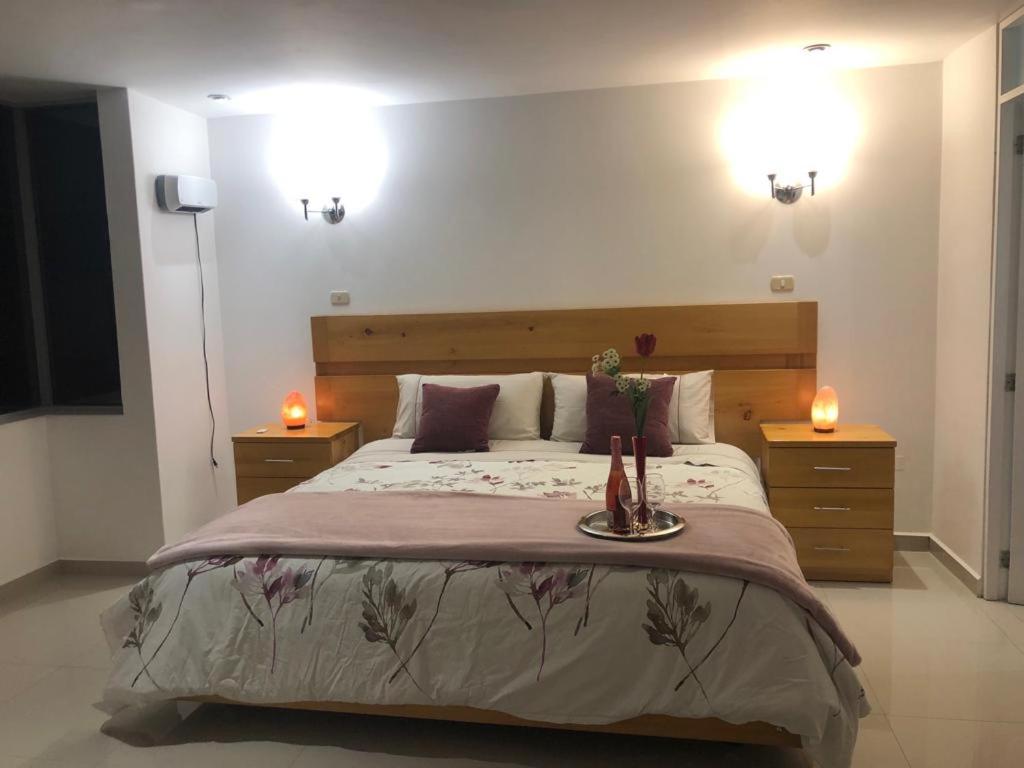 a bedroom with a large bed with two candles at HOTEL CB CAJAMARCA HUACARIZ in Cajamarca