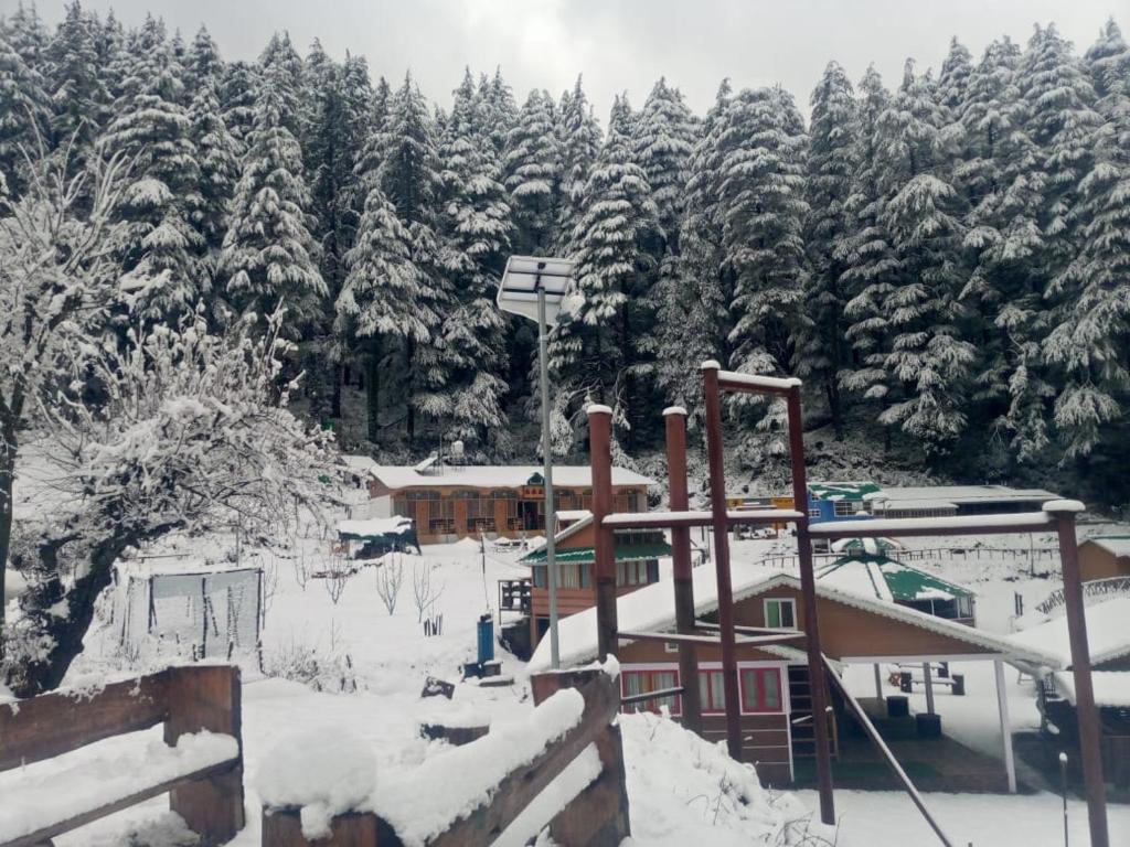 a ski lodge with snow covered trees in the background at Kanasar Jungle Camp & Retreat in Dehradun