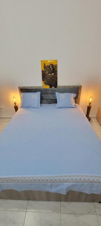 Una cama blanca con dos almohadas encima. en Residence Lyne en Kairouan