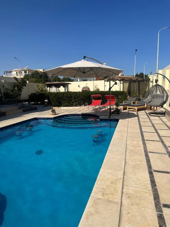 een zwembad met stoelen en een parasol bij Alis Villa in Hurghada