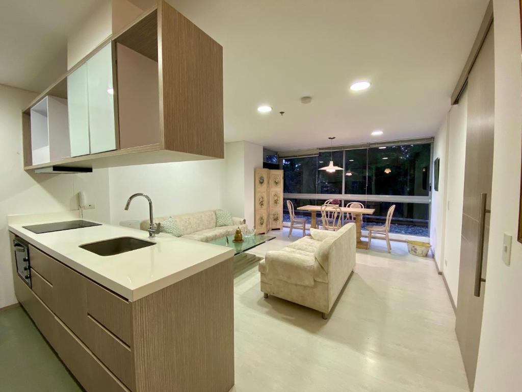 a kitchen with a sink and a living room at Apartaestudio cercano al aeropuerto. in Rionegro