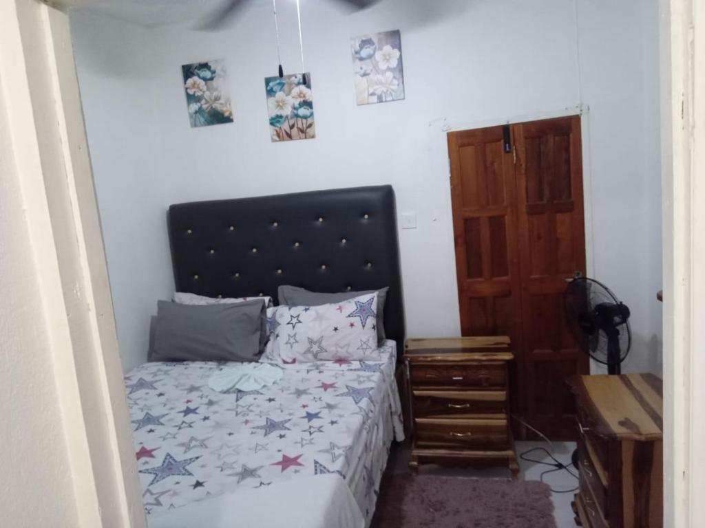 a small bedroom with a bed and a wooden door at Chic Vybz Deluxe in Four Mile