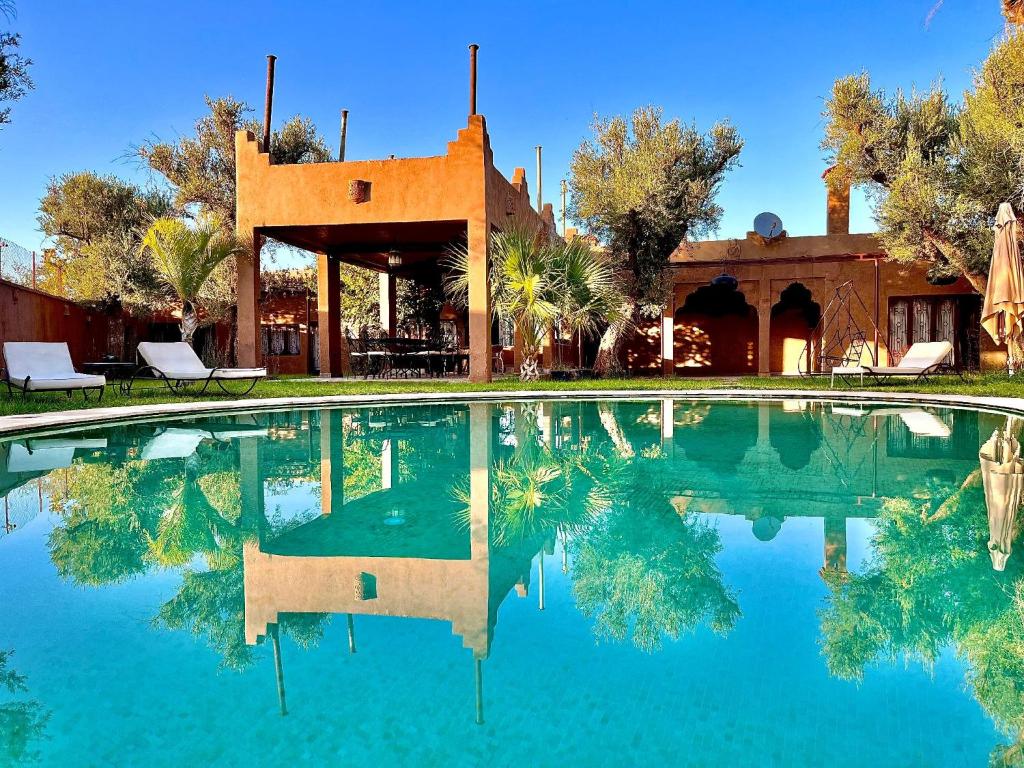 a swimming pool in front of a house with trees at Whisper in Marrakech