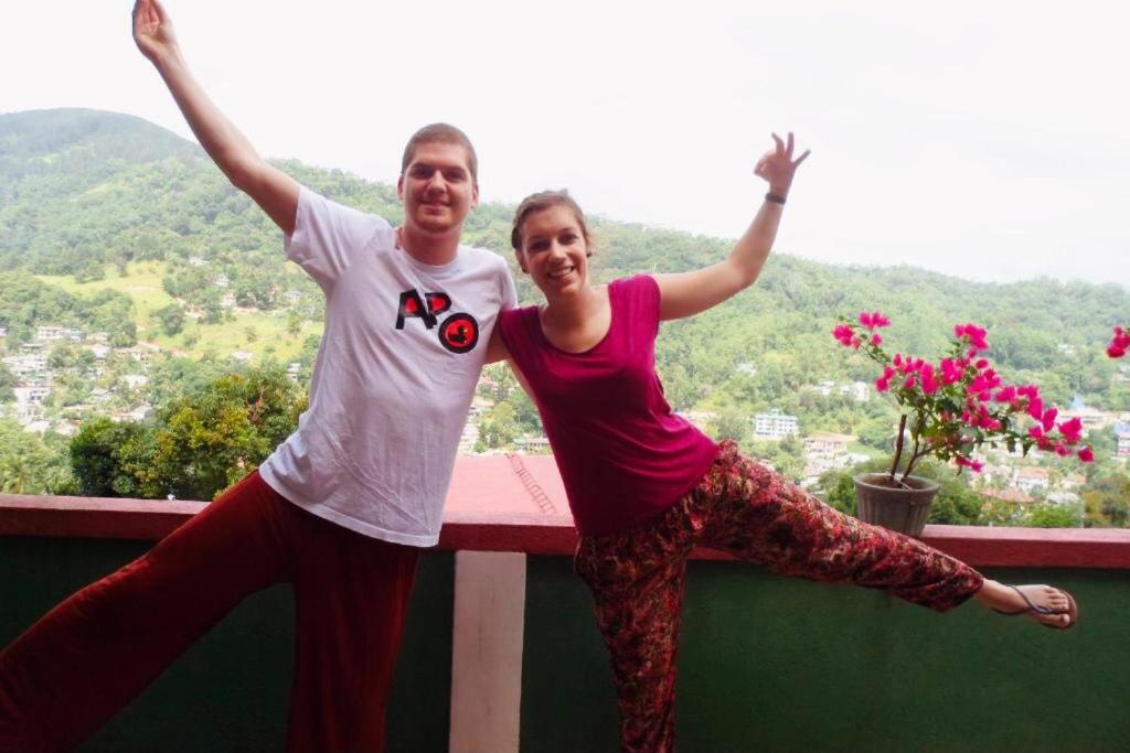 Un uomo e una donna in piedi su un cornicione con le braccia in aria di Mountain View a Kandy