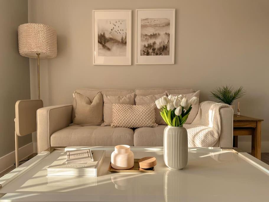 una sala de estar con sofá y un jarrón de flores en Grand Union Apartment en Leicester
