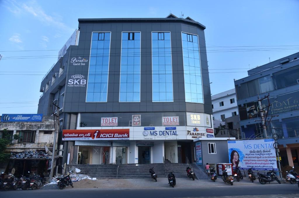 un edificio alto con motos estacionadas frente a él en The Paradise Guest Inn, en Nellore